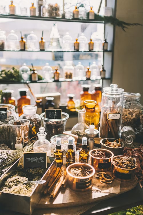 A traditional apothecary counter with dried herbs, dropper bottles, amber jars, and small chalkboard labels.