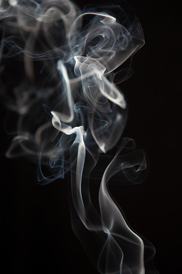 A column of pale smoke rising against pure black.