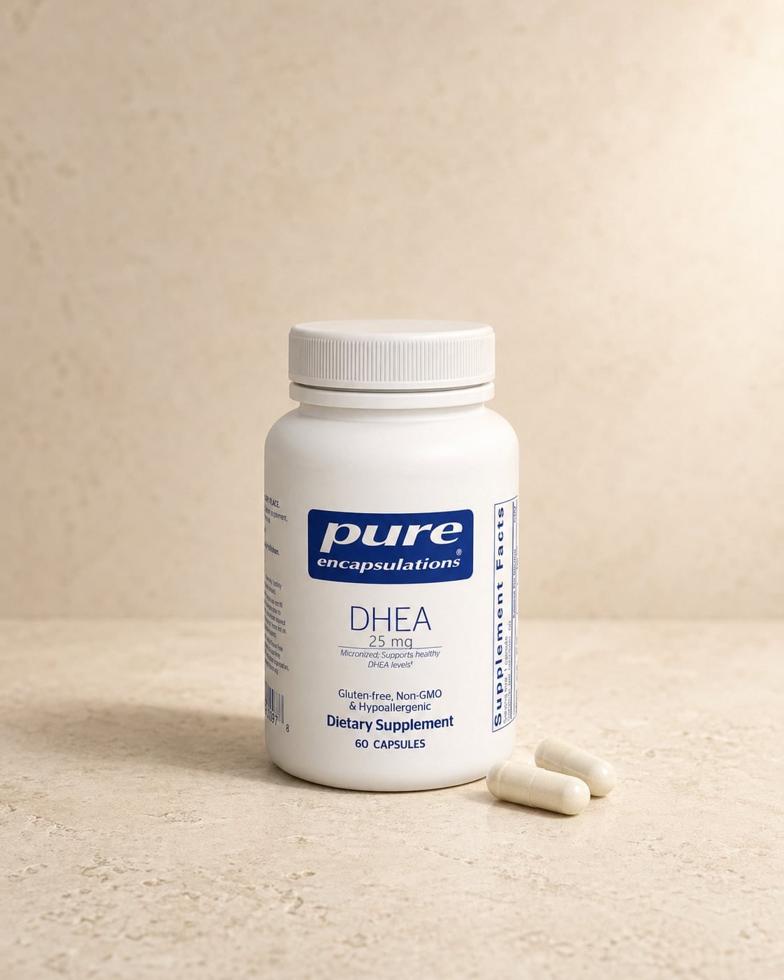 Pure Encapsulations DHEA 25mg bottle on a warm beige stone surface with two white capsules resting beside it